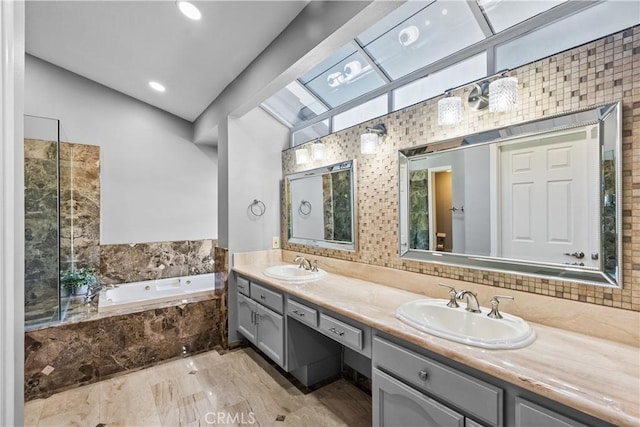 full bath with double vanity, a garden tub, vaulted ceiling, and a sink