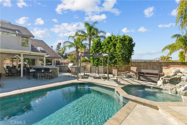 view of pool featuring a patio, outdoor dry bar, fence, a pool with connected hot tub, and a pergola