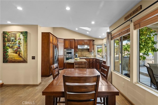 dining area featuring light wood-style floors, vaulted ceiling with skylight, baseboards, and recessed lighting