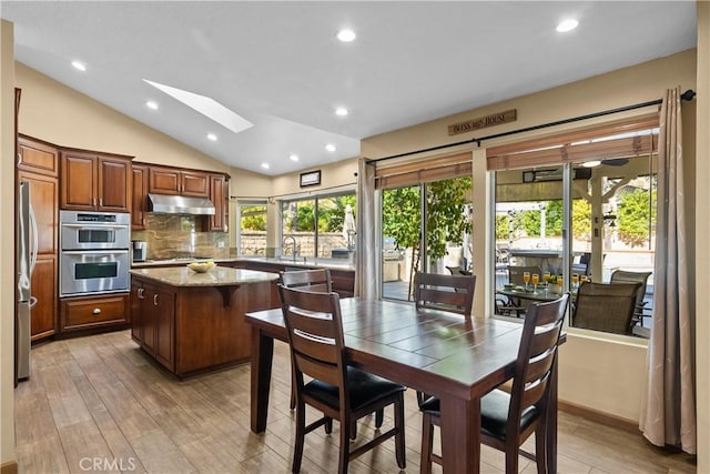 kitchen featuring a healthy amount of sunlight, under cabinet range hood, a kitchen island, and appliances with stainless steel finishes