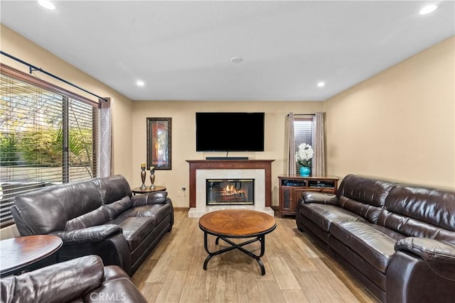 living room featuring light wood finished floors, a premium fireplace, and recessed lighting