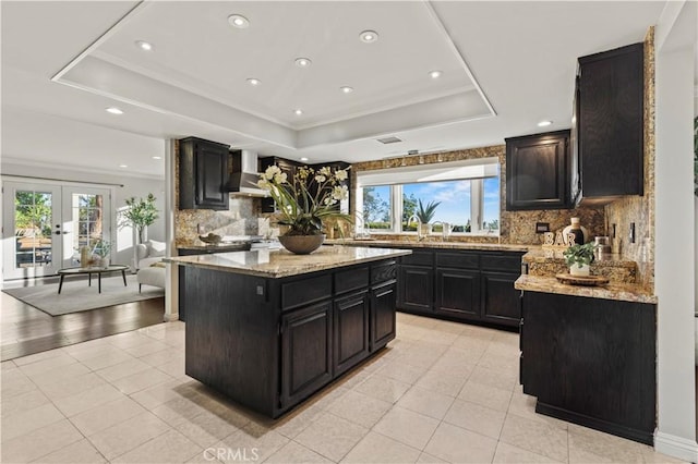 5386 Harter Ln, La Canada Flintridge, CA 91011 - kitchen featuring a tray ceiling, light tile patterned floors, dark cabinets, backsplash, and french doors