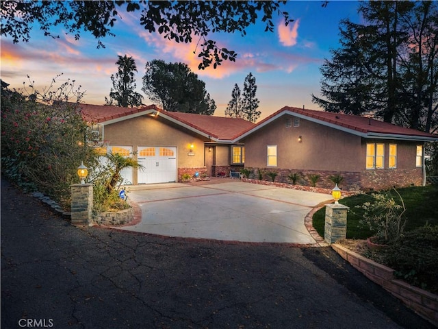 single story home featuring driveway, an attached garage, a tile roof, and stucco siding