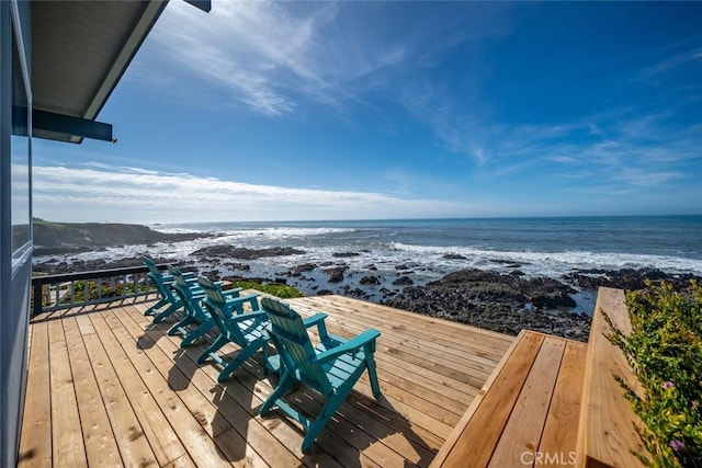 wooden terrace featuring a water view and a beach view