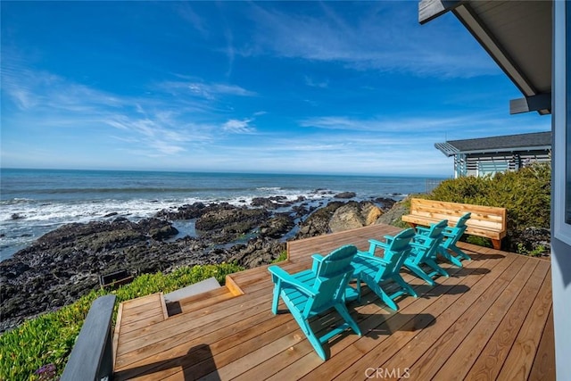 wooden deck with a water view, a beach view, and outdoor dining space