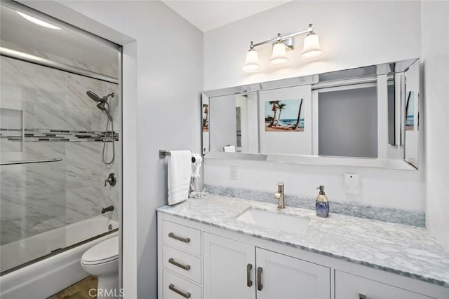 bathroom with enclosed tub / shower combo, vanity, and toilet
