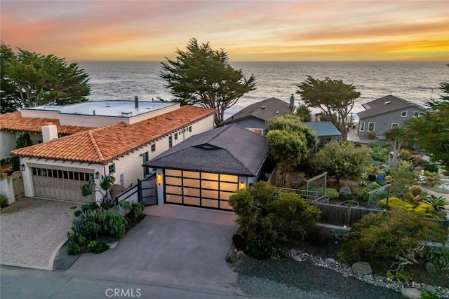 view of front of home with a garage, a tile roof, a water view, and fence