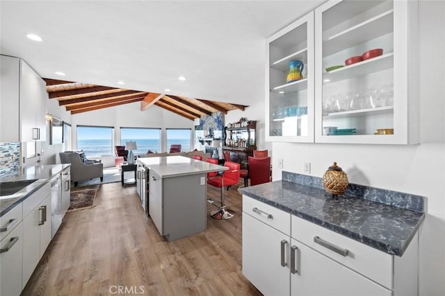 kitchen with a kitchen island, open floor plan, a water view, a kitchen bar, and white cabinetry