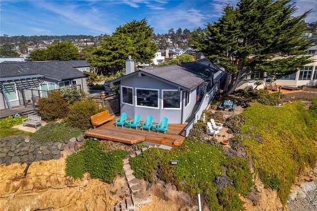 rear view of property with stucco siding, a chimney, and a wooden deck