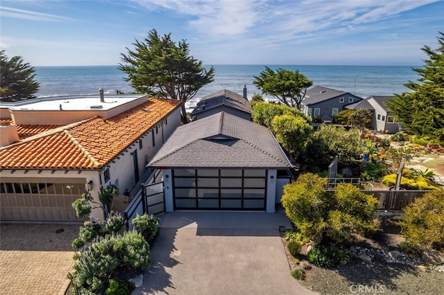 view of front of house with decorative driveway, a water view, an attached garage, and stucco siding