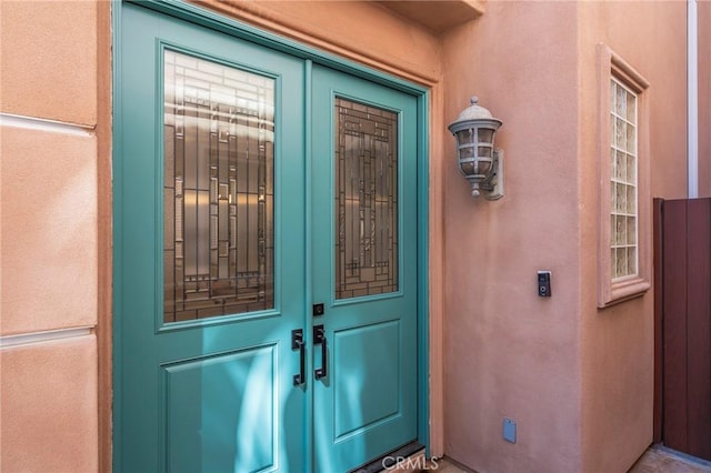 view of exterior entry featuring french doors and stucco siding