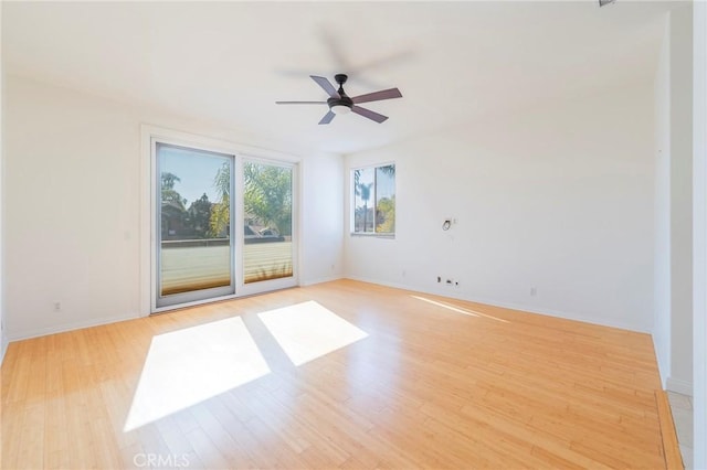 spare room featuring a ceiling fan, baseboards, and light wood finished floors