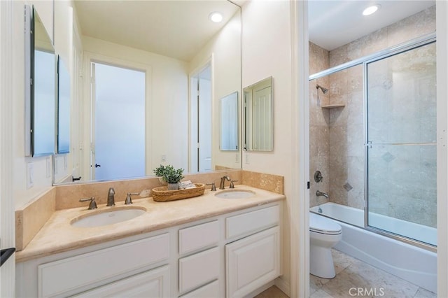 full bathroom featuring toilet, double vanity, enclosed tub / shower combo, and a sink