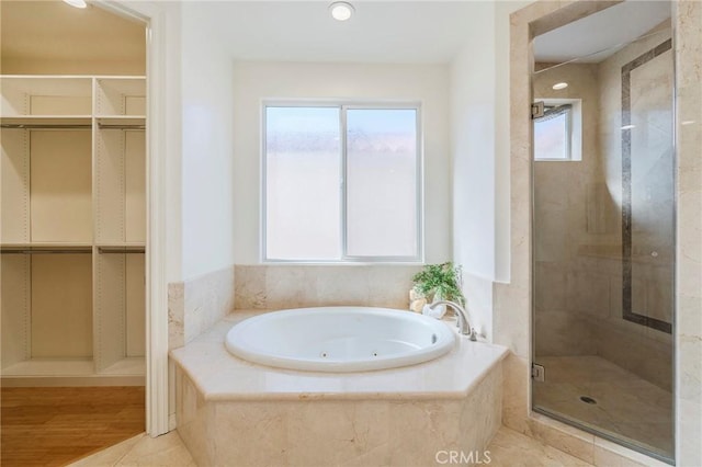 bathroom featuring a healthy amount of sunlight, a garden tub, a spacious closet, and a shower stall