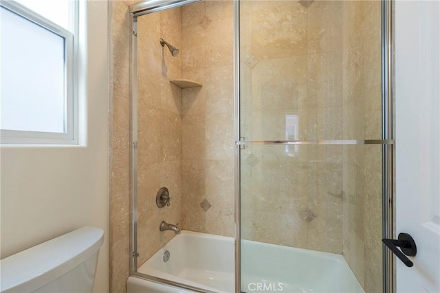 bathroom featuring bath / shower combo with glass door and toilet