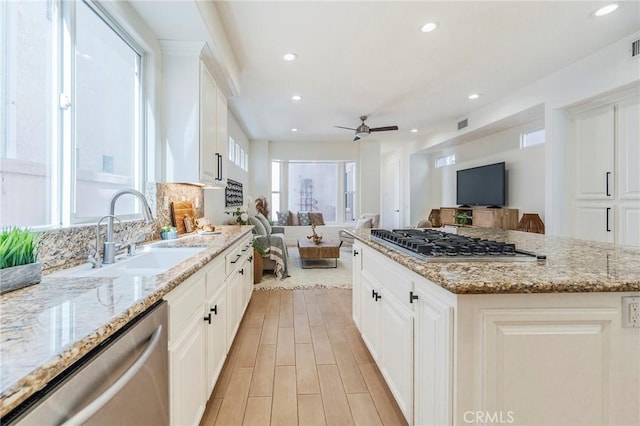 kitchen with white cabinets, appliances with stainless steel finishes, open floor plan, and a sink