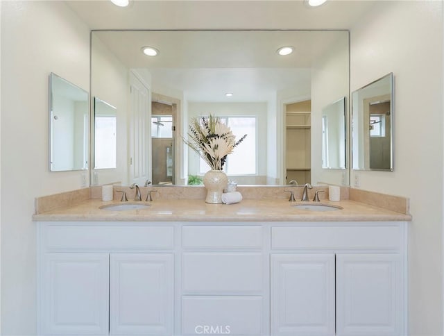 full bath featuring double vanity, a sink, and recessed lighting