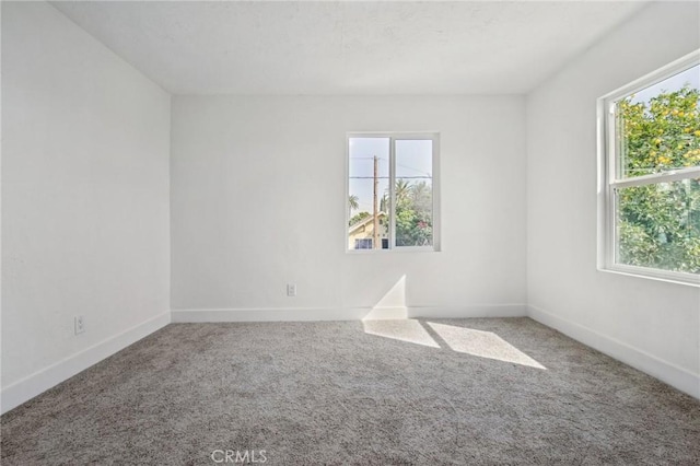 spare room featuring carpet and baseboards