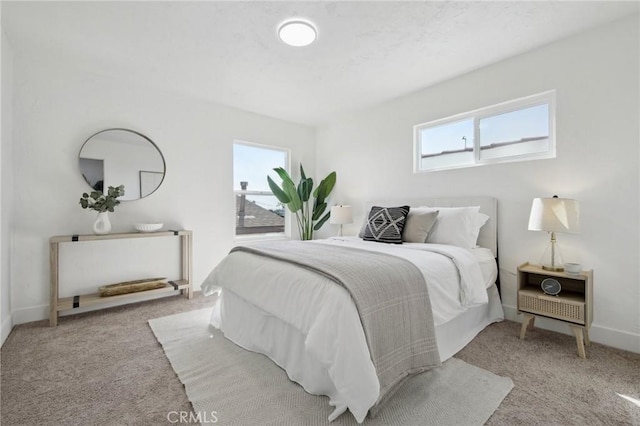 bedroom with light carpet, multiple windows, and baseboards