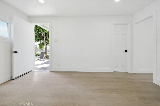 spare room featuring recessed lighting, light wood-type flooring, and baseboards