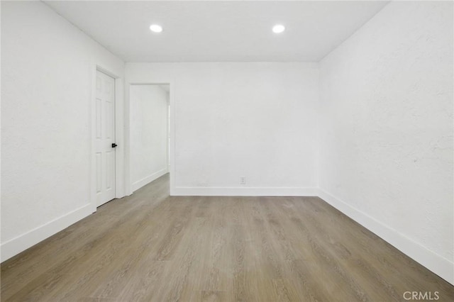 spare room featuring baseboards, wood finished floors, and recessed lighting