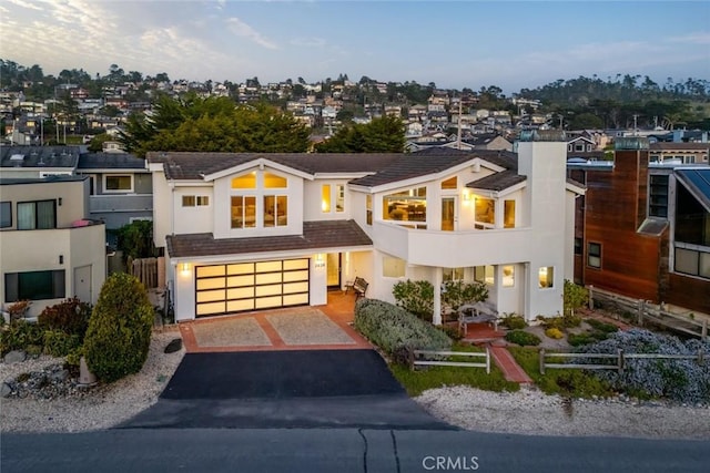 view of front of property featuring a chimney, stucco siding, fence, a garage, and driveway