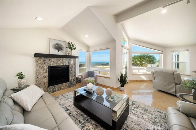 living area featuring lofted ceiling, a water view, a high end fireplace, and baseboards