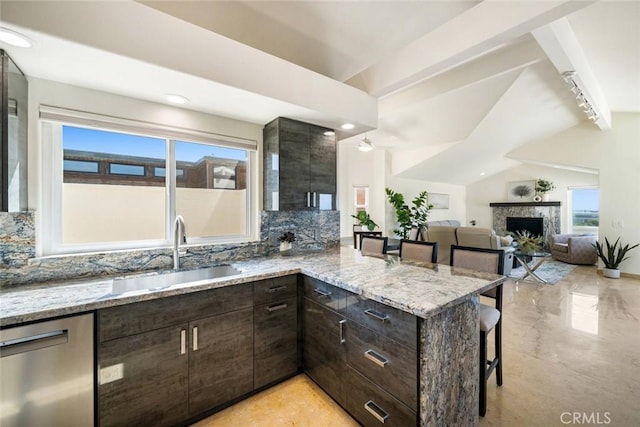 kitchen featuring light stone counters, stainless steel dishwasher, a sink, a peninsula, and a kitchen bar