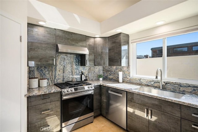 kitchen with dark brown cabinetry, appliances with stainless steel finishes, light stone counters, ventilation hood, and a sink