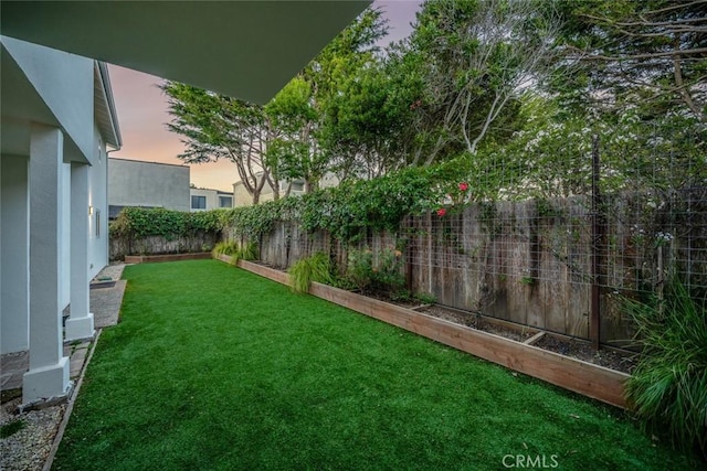 yard at dusk featuring a fenced backyard