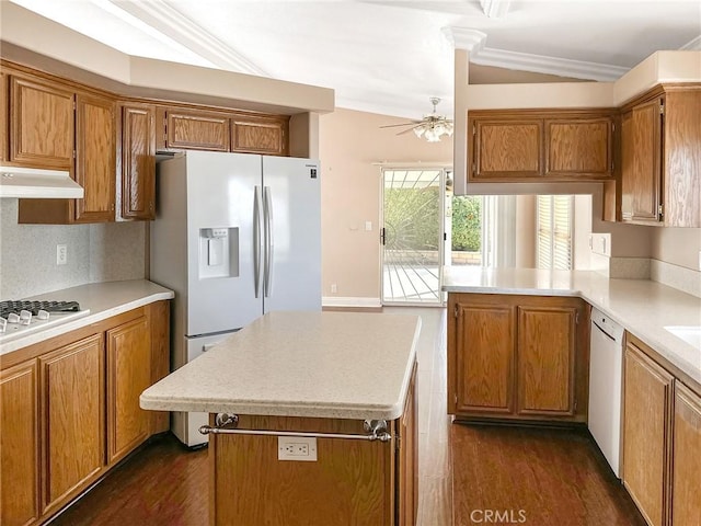 kitchen featuring under cabinet range hood, light countertops, and brown cabinetry