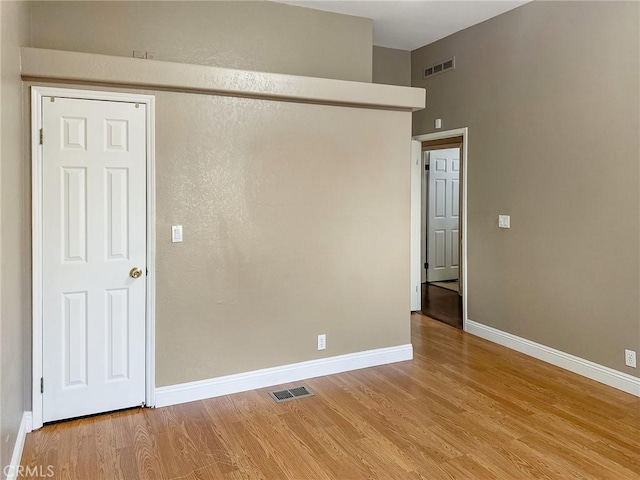 unfurnished room featuring visible vents, baseboards, and wood finished floors