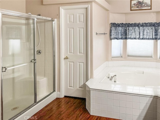 full bathroom featuring a garden tub, a shower stall, and wood finished floors