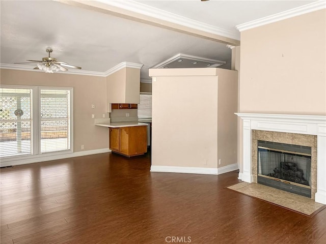 unfurnished living room featuring a fireplace, a ceiling fan, baseboards, dark wood-style floors, and crown molding