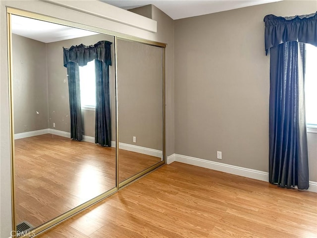 unfurnished bedroom with a closet, baseboards, and wood finished floors