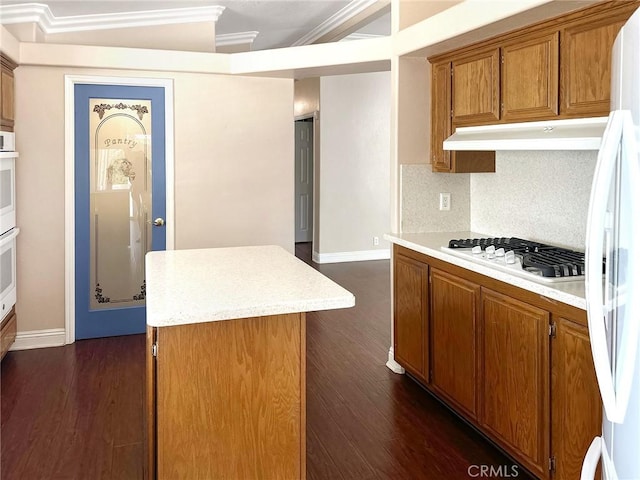 kitchen featuring white appliances, brown cabinets, a center island, light countertops, and under cabinet range hood