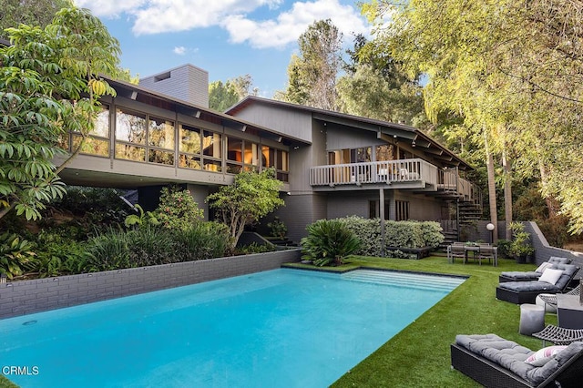 outdoor pool featuring outdoor lounge area, a yard, and stairway