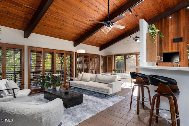 living area with track lighting, high vaulted ceiling, wooden ceiling, beamed ceiling, and dark tile patterned floors