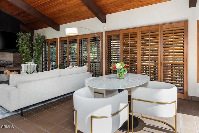 interior space with vaulted ceiling with beams, dark tile patterned floors, and wooden ceiling