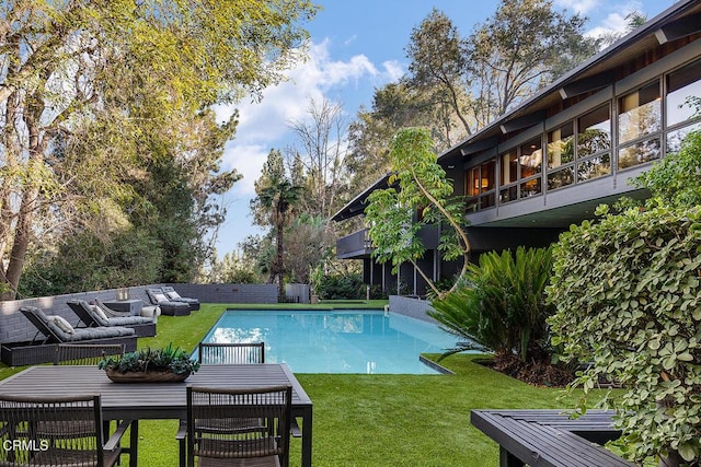 view of swimming pool with a fenced in pool and a lawn