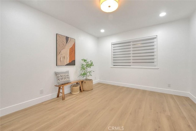 empty room with baseboards, wood finished floors, and recessed lighting