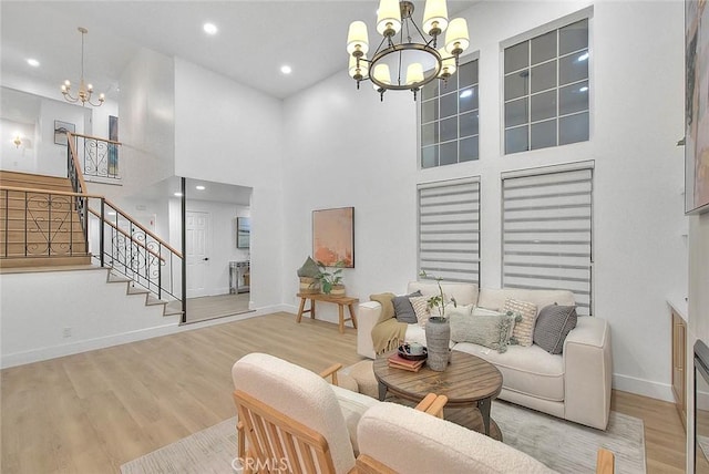 living area with an inviting chandelier, light wood-style flooring, stairs, and baseboards