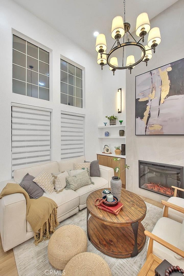 living room with a chandelier, wood finished floors, and a tile fireplace