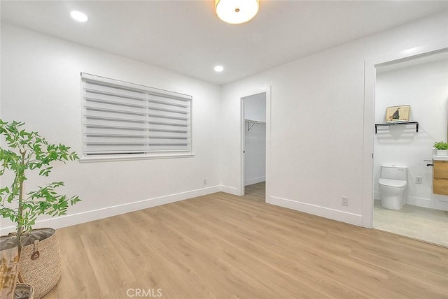 unfurnished bedroom featuring recessed lighting, baseboards, a spacious closet, and light wood finished floors