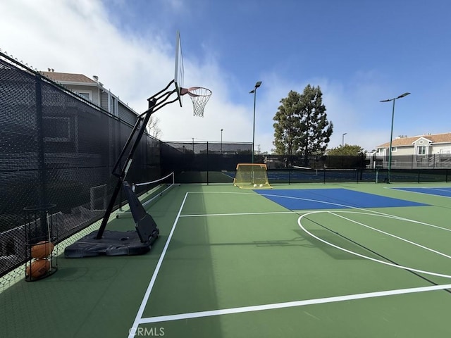 view of sport court featuring a tennis court, community basketball court, and fence