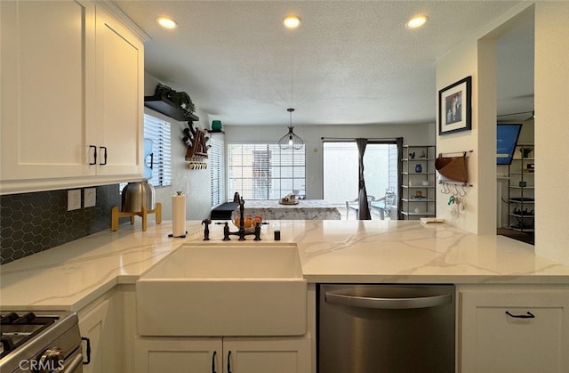 kitchen with recessed lighting, a peninsula, a sink, stainless steel dishwasher, and light stone countertops