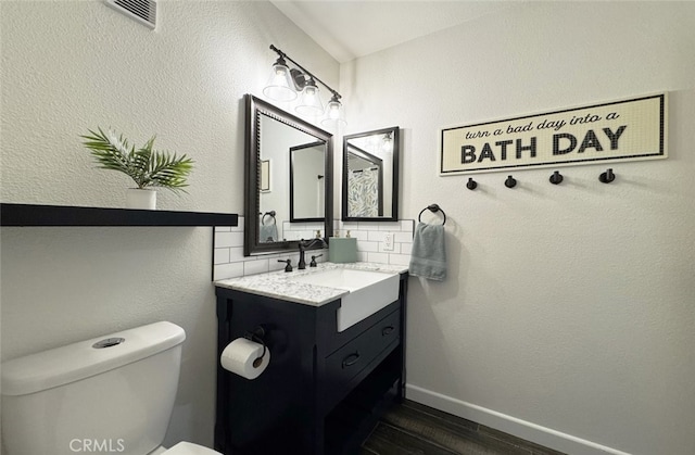 bathroom featuring visible vents, toilet, vanity, wood finished floors, and baseboards