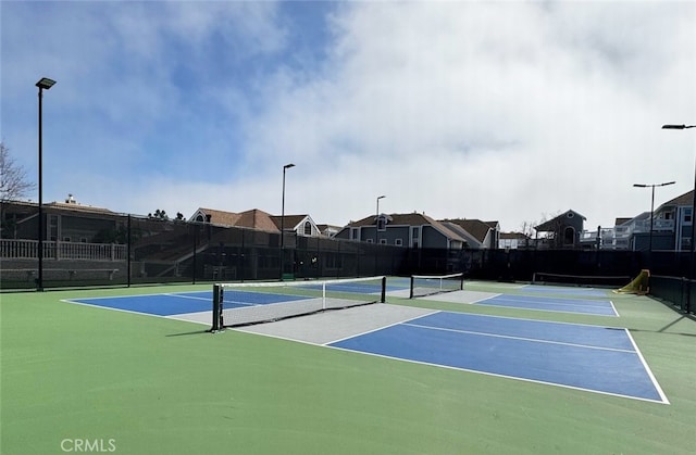 view of tennis court featuring community basketball court and fence