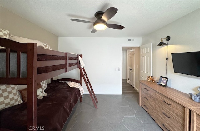 tiled bedroom with baseboards, ceiling fan, visible vents, and a textured ceiling