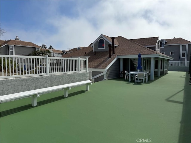 back of house featuring roof with shingles